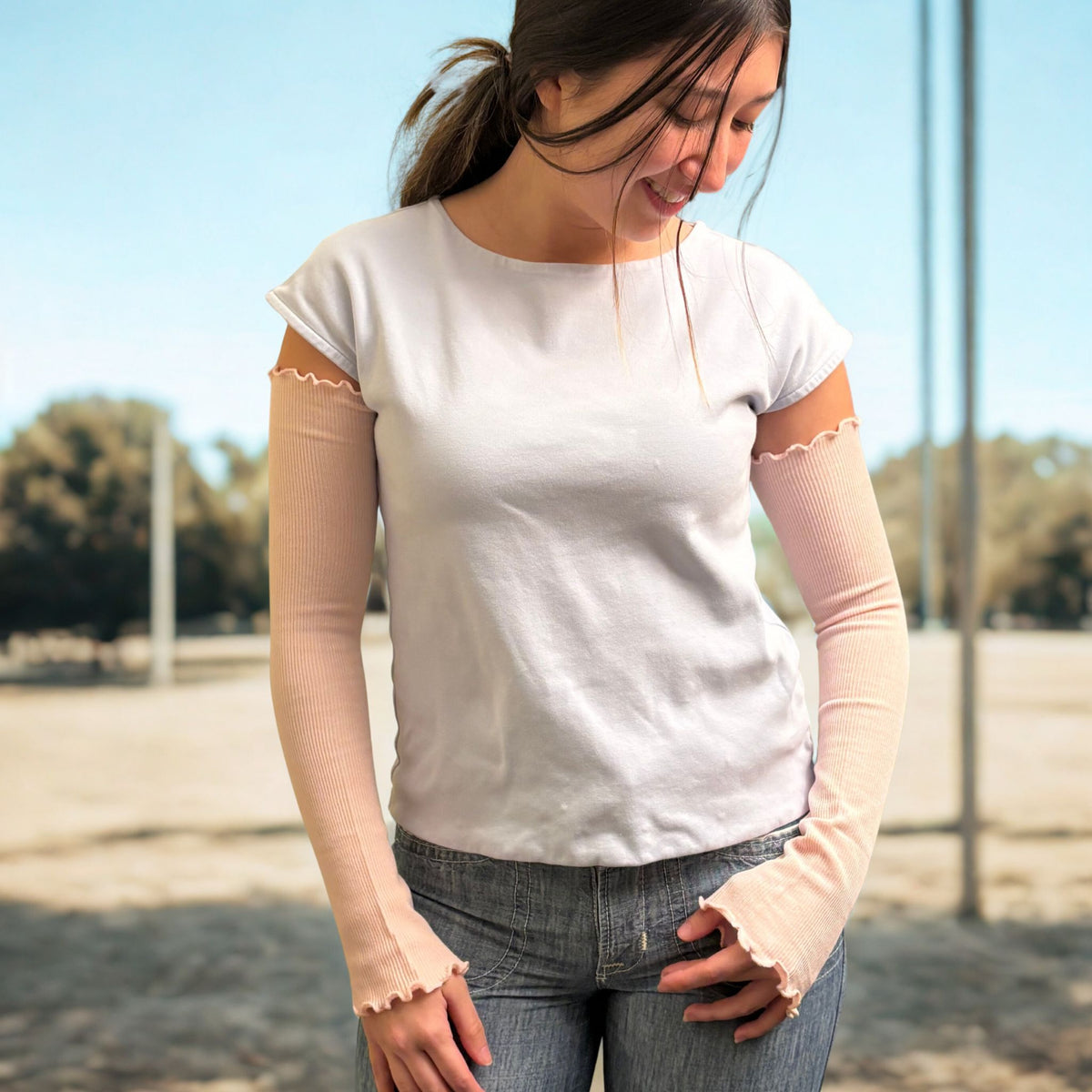 Woman standing outside park covering arm with UV protection arm cover