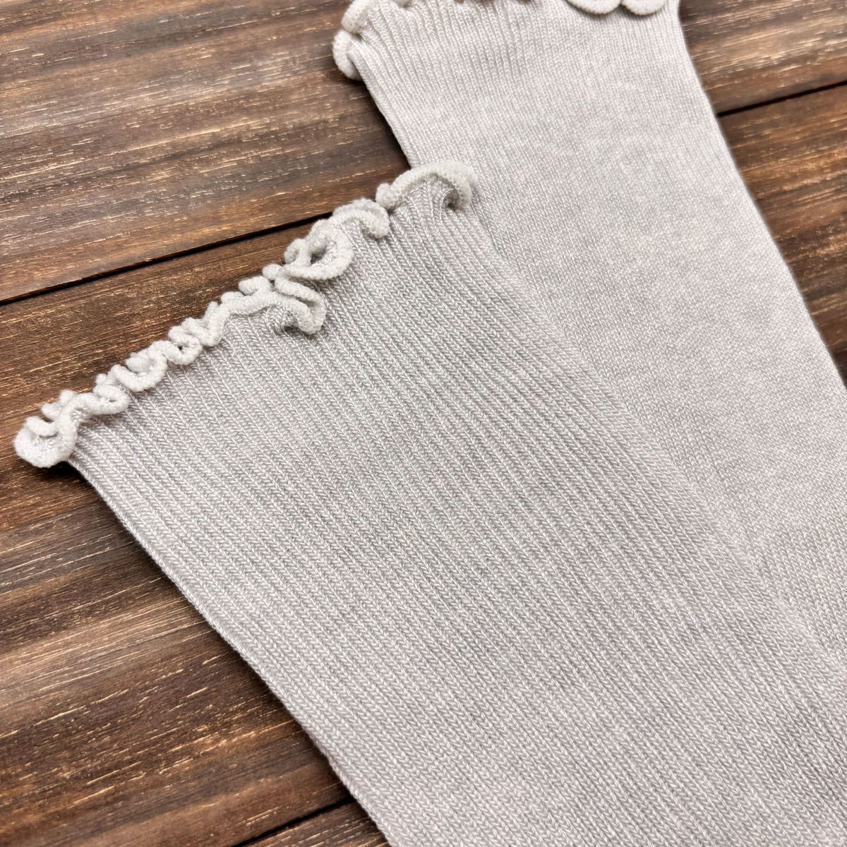 Gray arm cover with decorative trim on a wooden surface