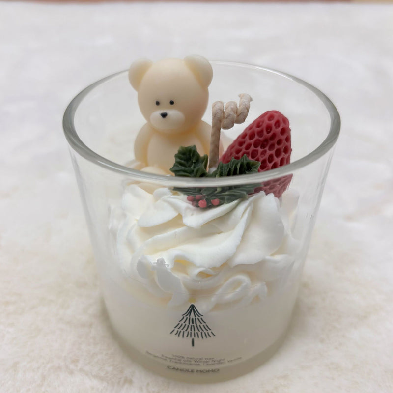 Candle with a bear and strawberry decoration on a white surface