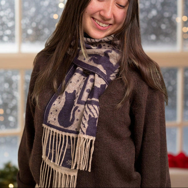 Woman wearing a patterned scarf with fringe, standing.