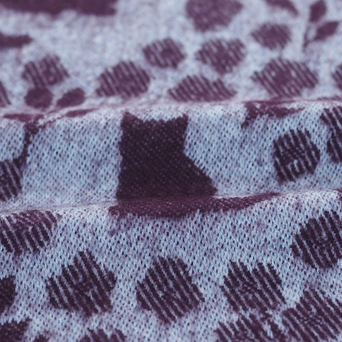 Close-up of fabric with a purple cat pattern on a light background