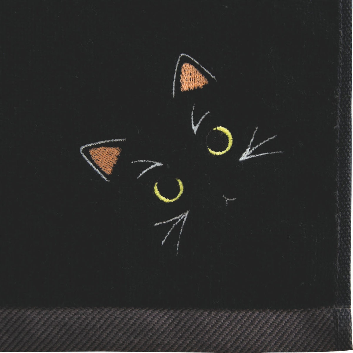 Black face towel with embroidered cat design on a black background