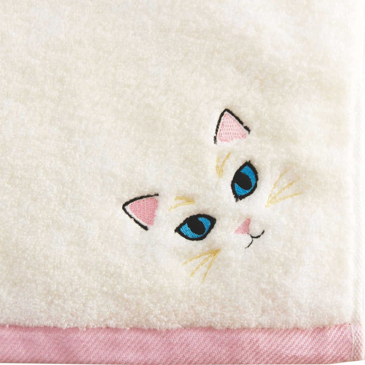 Embroidered cat face design on a white towel