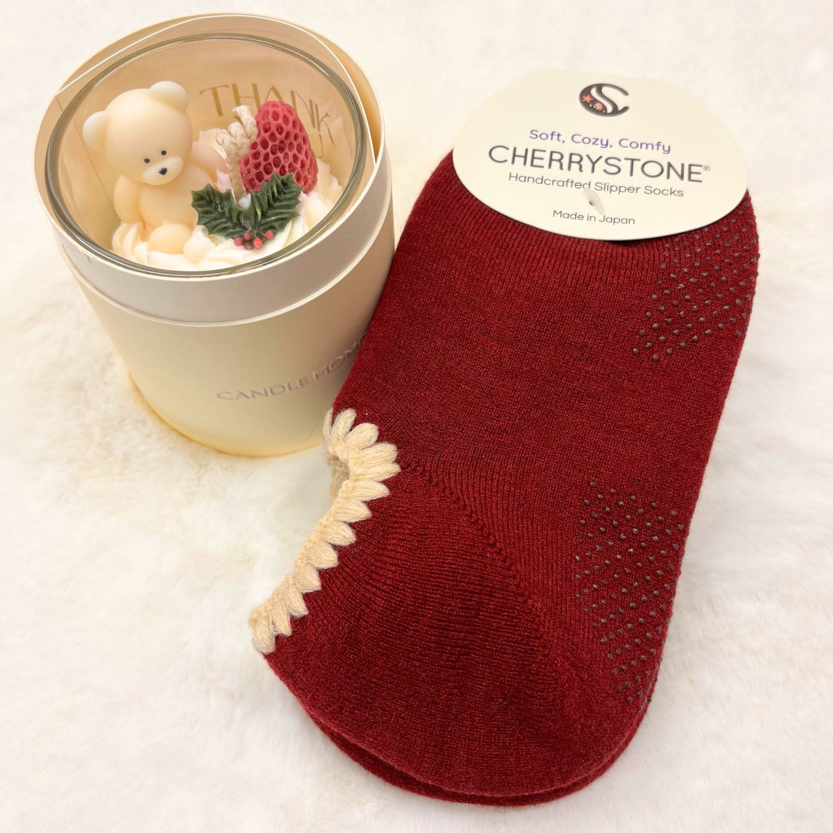 Dark Red slipper socks next to a small candle