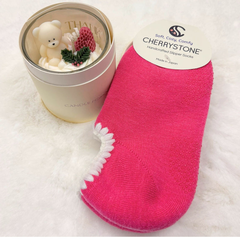 Pink socks with white trim next to candle