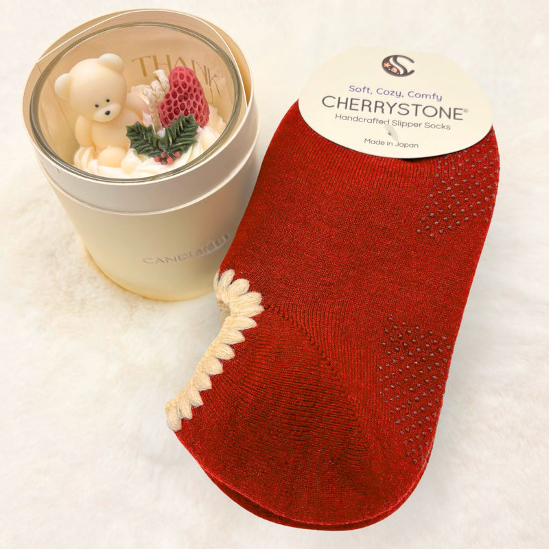 Red slipper socks next to a small candle