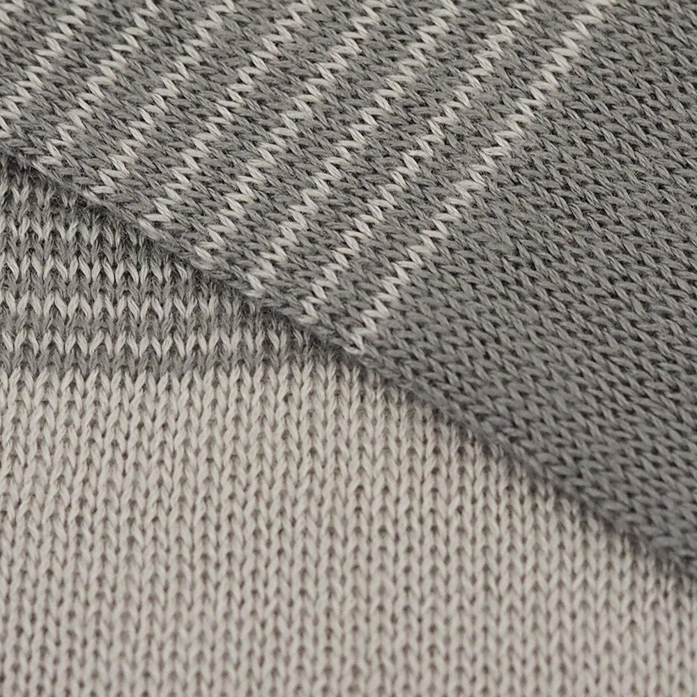 Close-up of gray and beige knitted fabric with a diagonal pattern