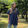 Model wearing lightweight 2-way tunic shirt with buttons at the back in smock-style silhouette.