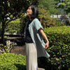 Model wearing lightweight 2-way utility tunic shirt with front buttons. Ripple-textured cotton fabric, short sleeves, relaxed fit.