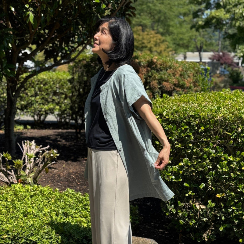 Model wearing lightweight 2-way utility tunic shirt with front buttons. Ripple-textured cotton fabric, short sleeves, relaxed fit.