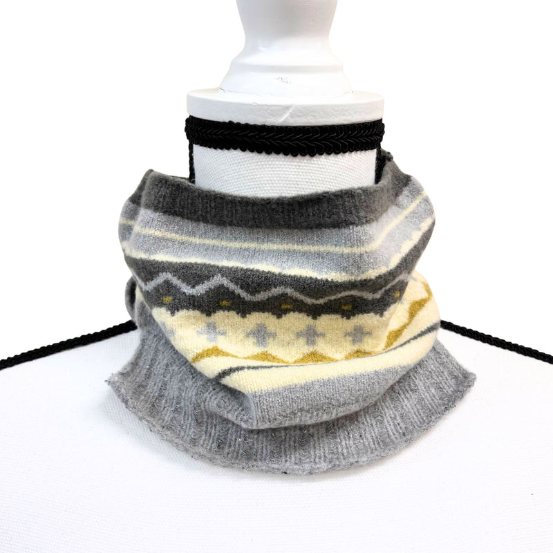 Stack of gray and white patterned scarves on a mannequin arm against a white background