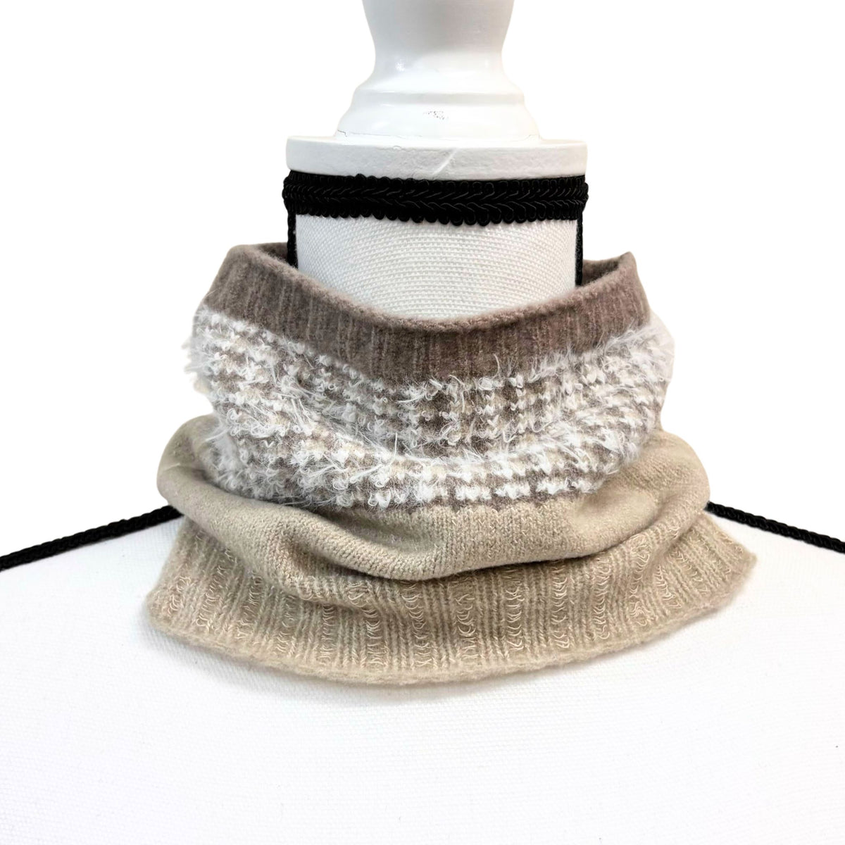 Knitted cowl in beige and white pattern on a mannequin with a white background