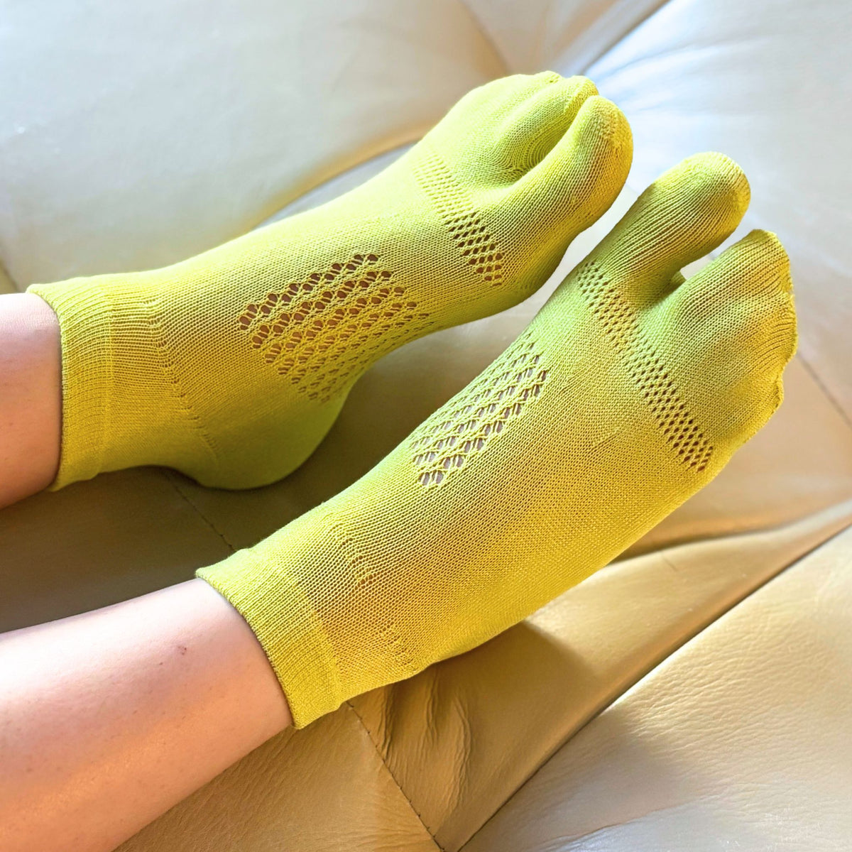 Yellow toe-separated socks on a person's feet with a light background