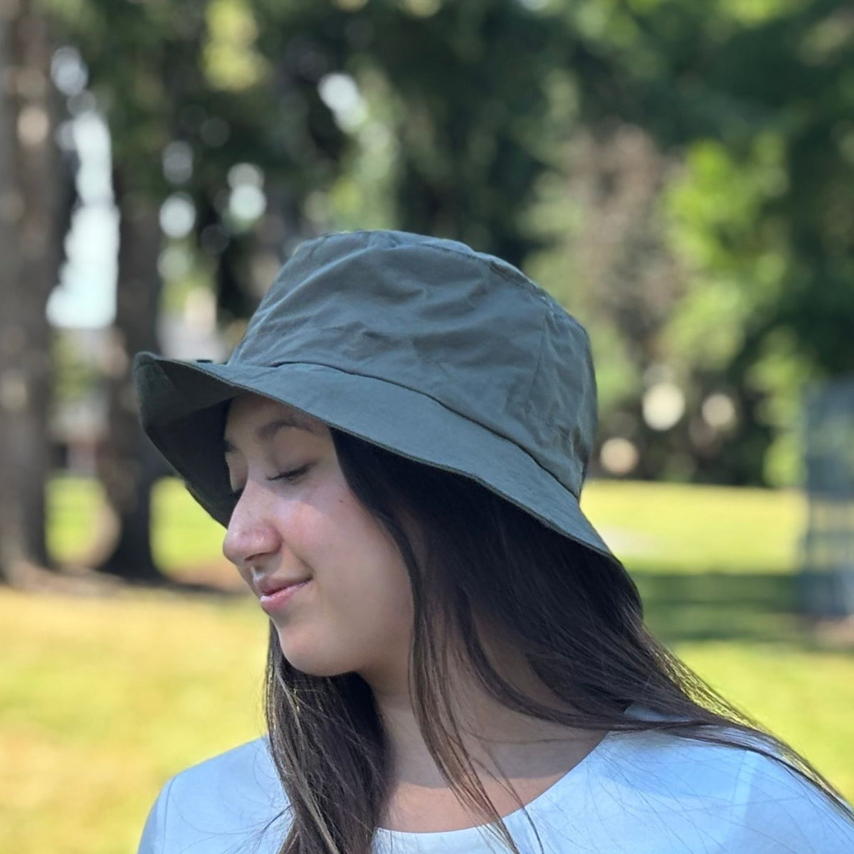 Person wearing a green bucket hat in a park setting