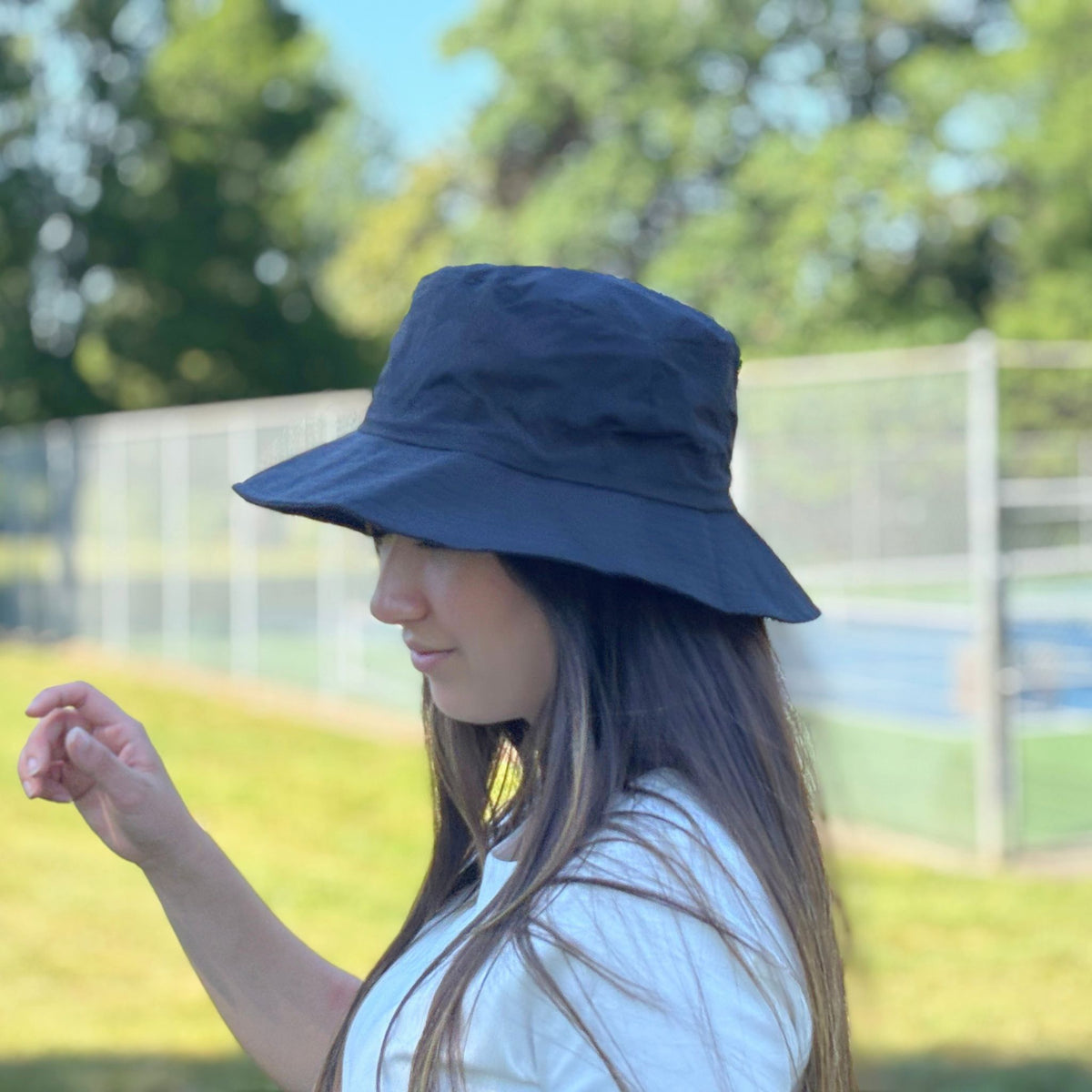 Person wearing a blue bucket hat outdoors with greenery in the background