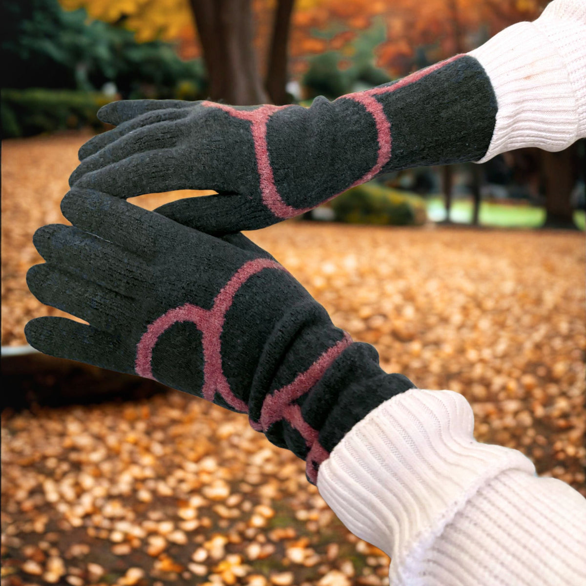 Black gloves with pink accents worn by a person against an autumn background
