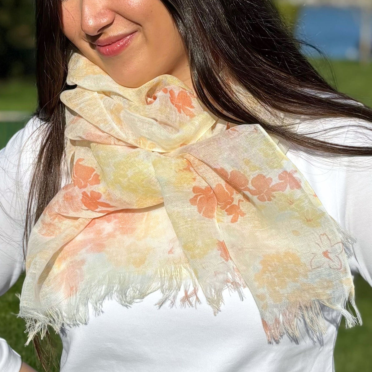 Woman wearing a floral scarf with a blurred outdoor background