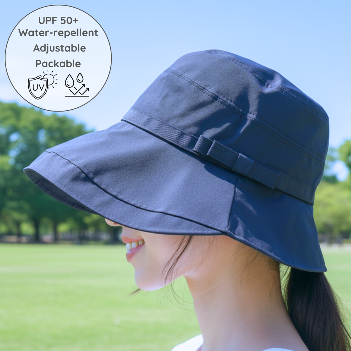 Person wearing a navy sun hat in an outdoor setting with trees and grass.