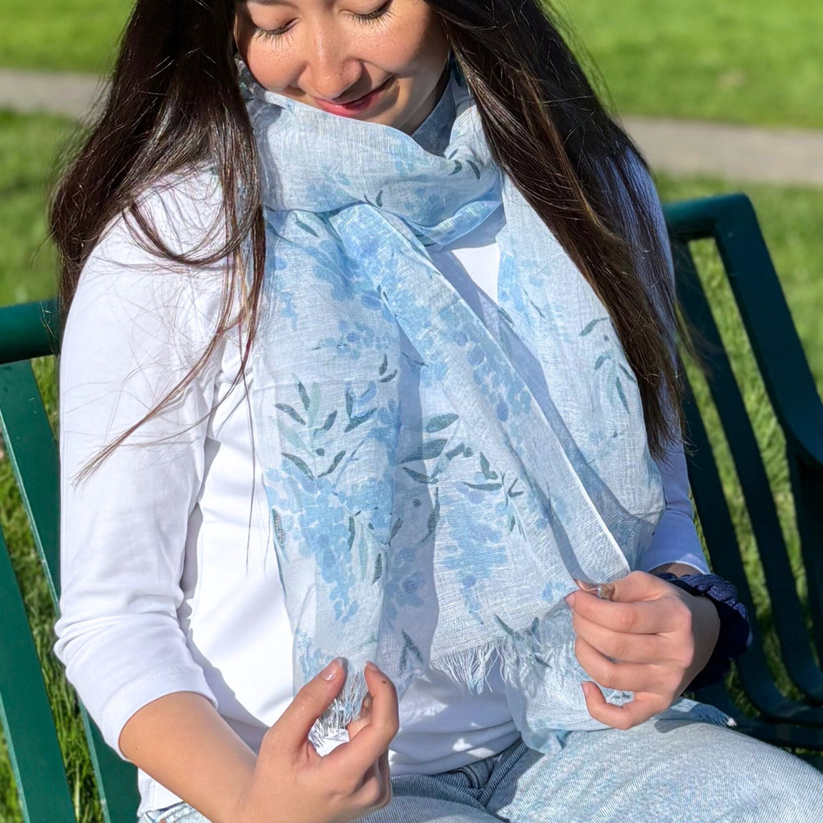 Woman sitting on a bench wearing a light blue floral scarf