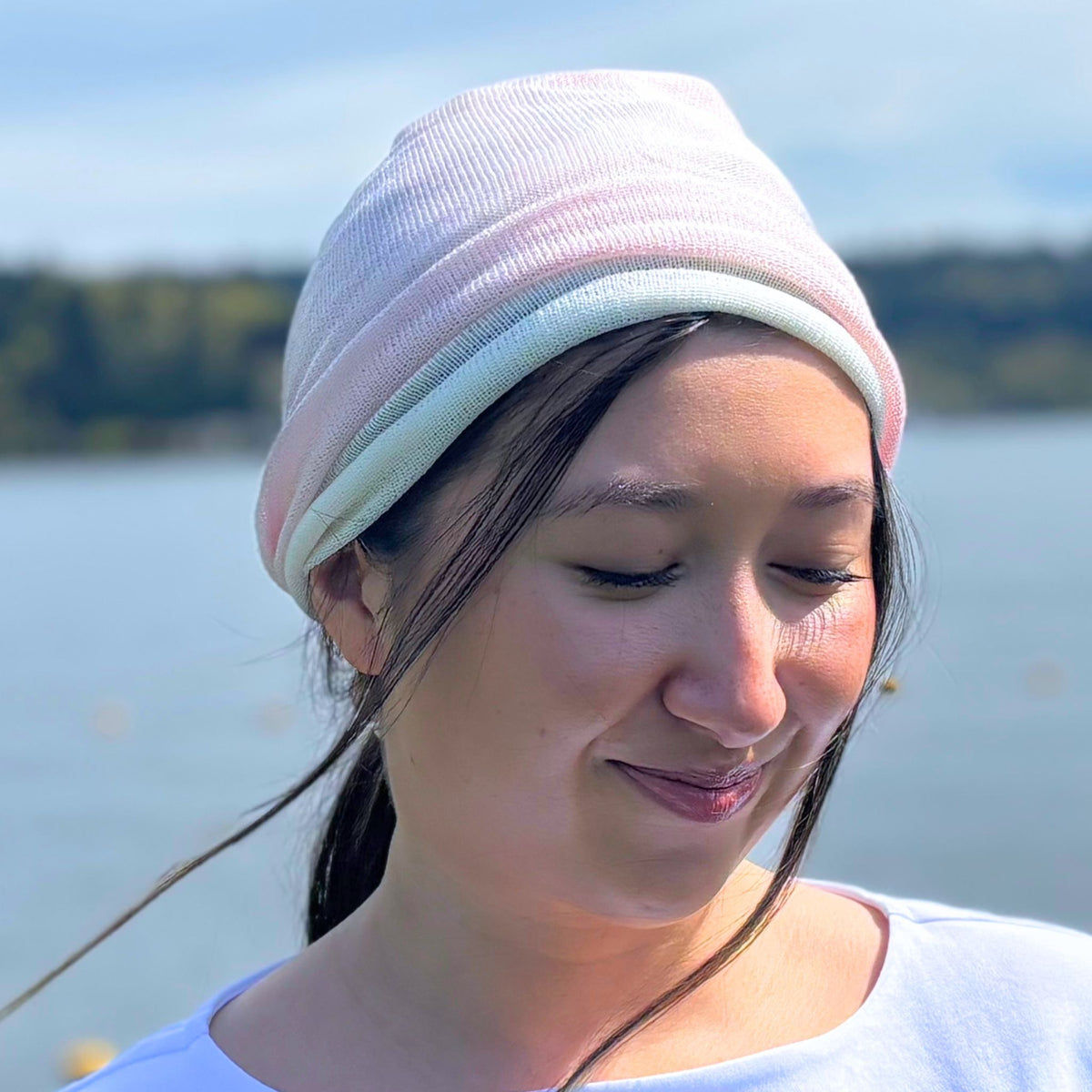 Woman wearing a pink silk beanie with a blurred natural background