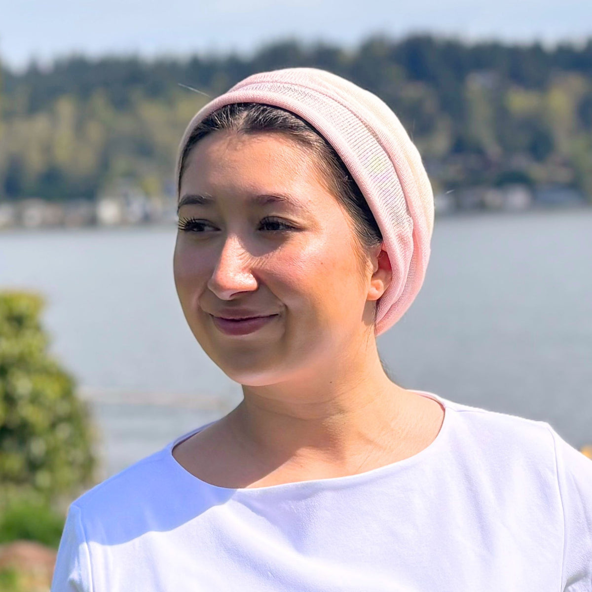 Woman wearing a pink headscarf with a lake and trees in the background