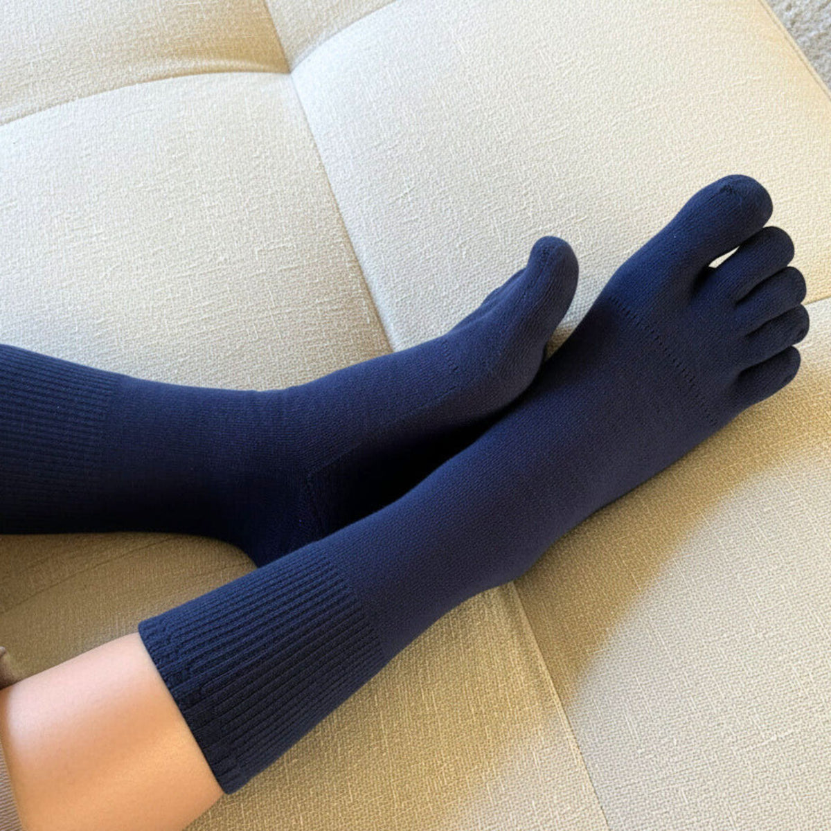 Navy blue 5-toe socks worn on a beige cushioned surface