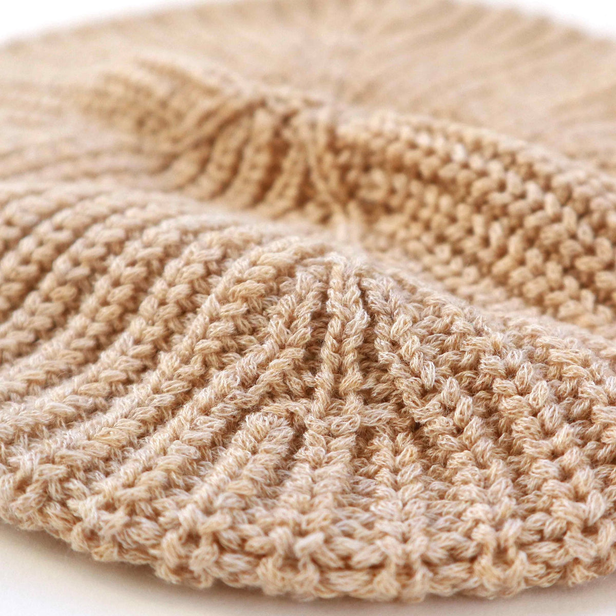 Close-up of a beige knitted beret on a light background