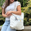 Person holding a tote bag with a Starry Night design and text.