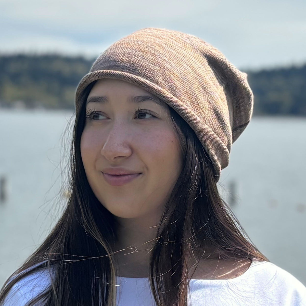 Woman wearing a brown silk beanie with a blurred natural background