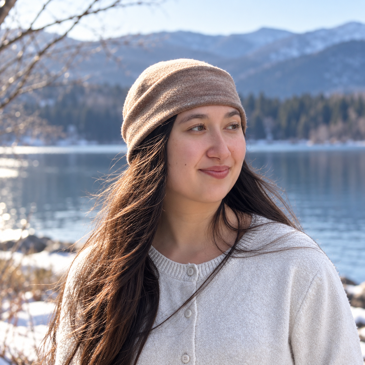 a Person wearing a gray silk beanie with a blurred lake and trees in the background