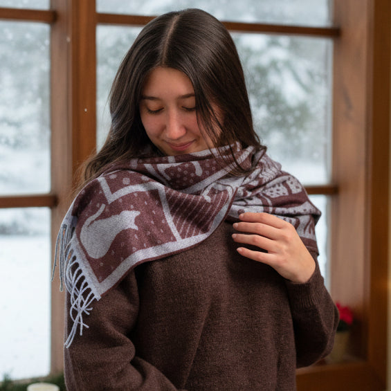 Woman wearing a patterned scarf in front of a window with a snowy view