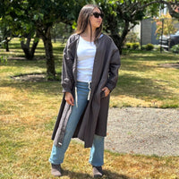 Person wearing a long coverall trench coat and in a park-like setting