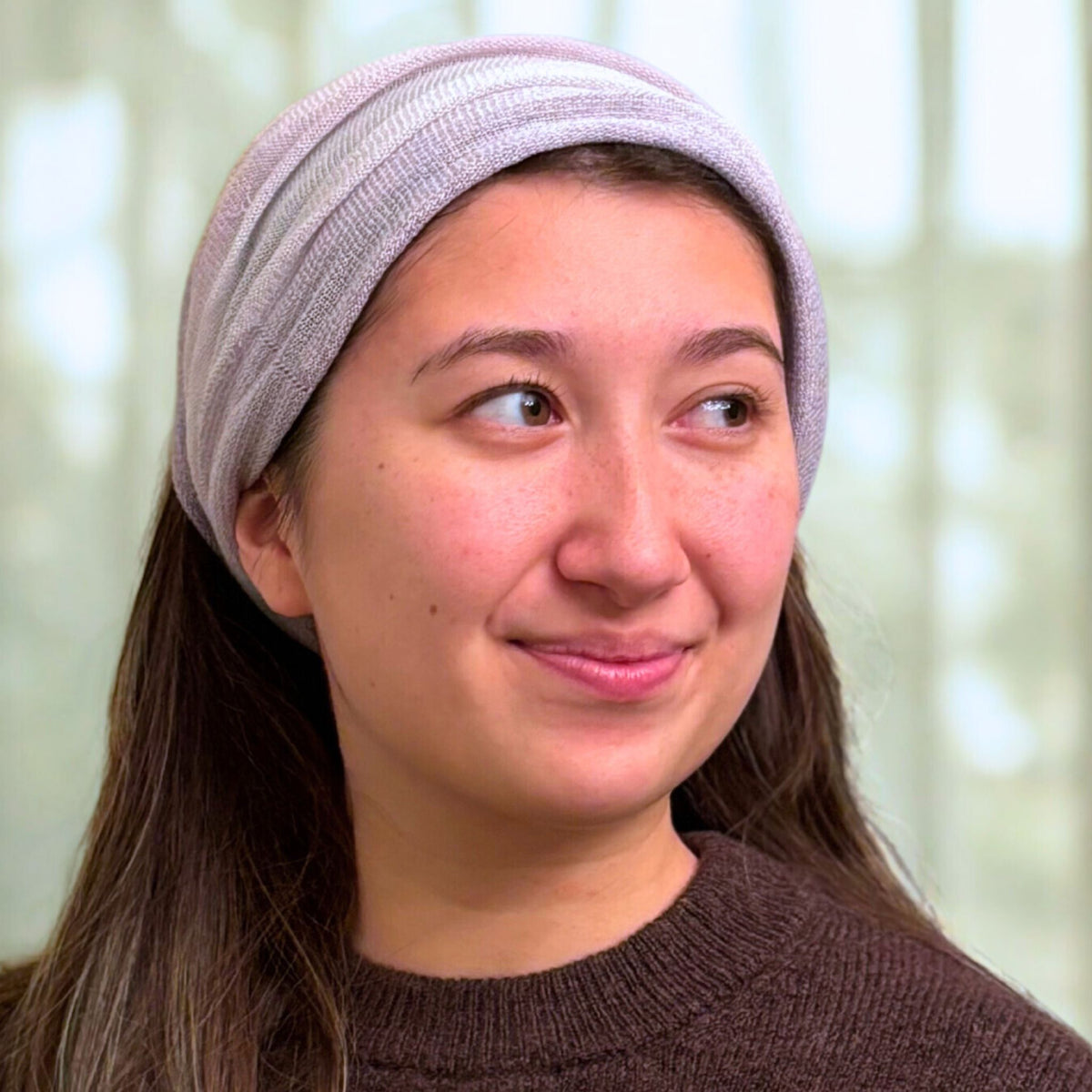Woman wearing a light purple headband against a blurred background