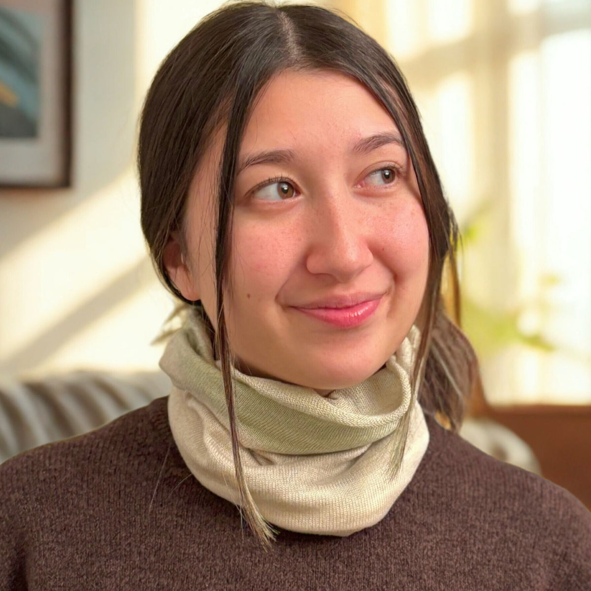 Woman wearing a light green scarf in a softly lit room