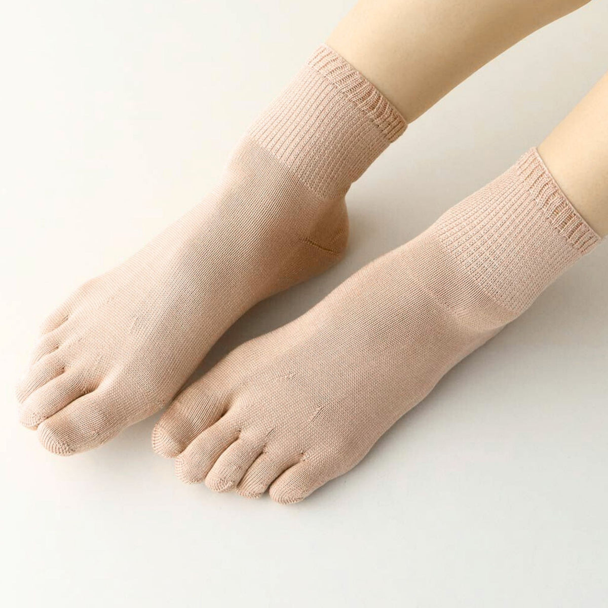 Beige toe-separated socks worn on feet against a light background