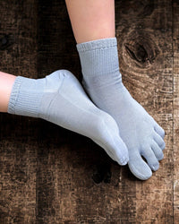 Pair of light blue five-finger socks on a wooden surface