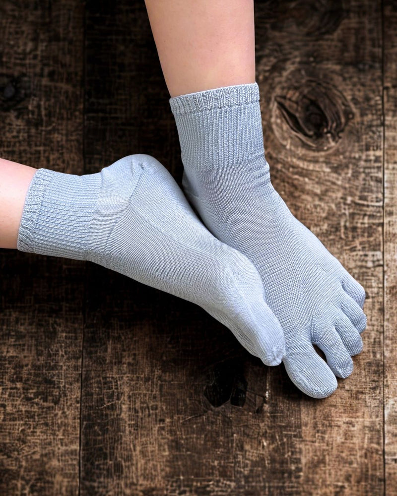 Pair of light blue five-finger socks on a wooden surface