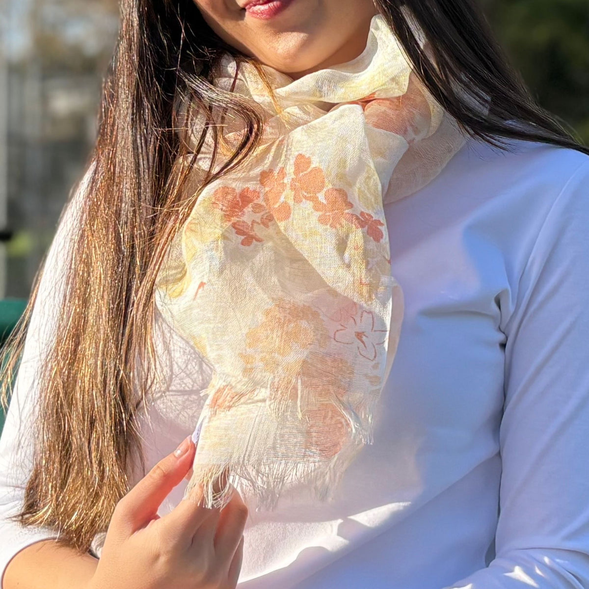 Woman wearing a floral scarf with a blurred outdoor background