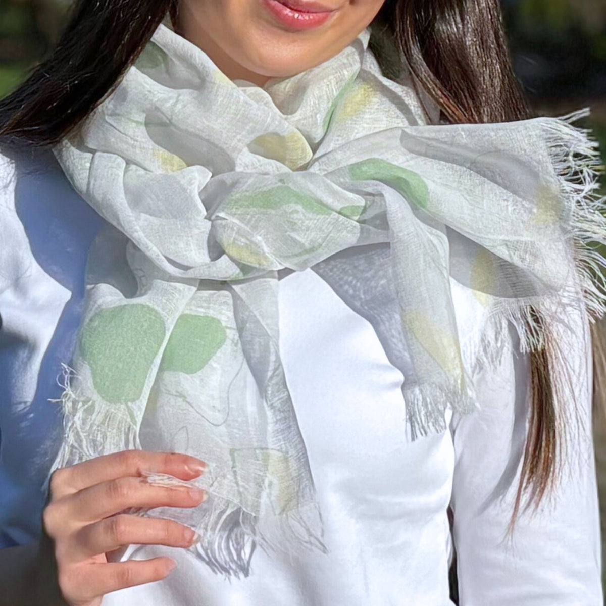 Person wearing a white scarf with a green pear pattern