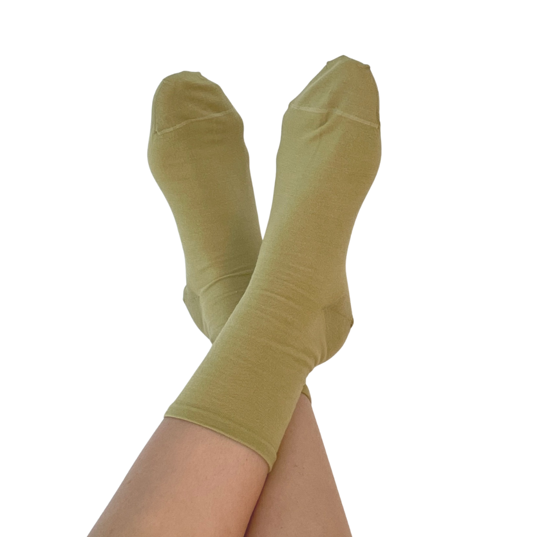 A pair of olive green crew socks worn on crossed legs, shown against a solid white background.