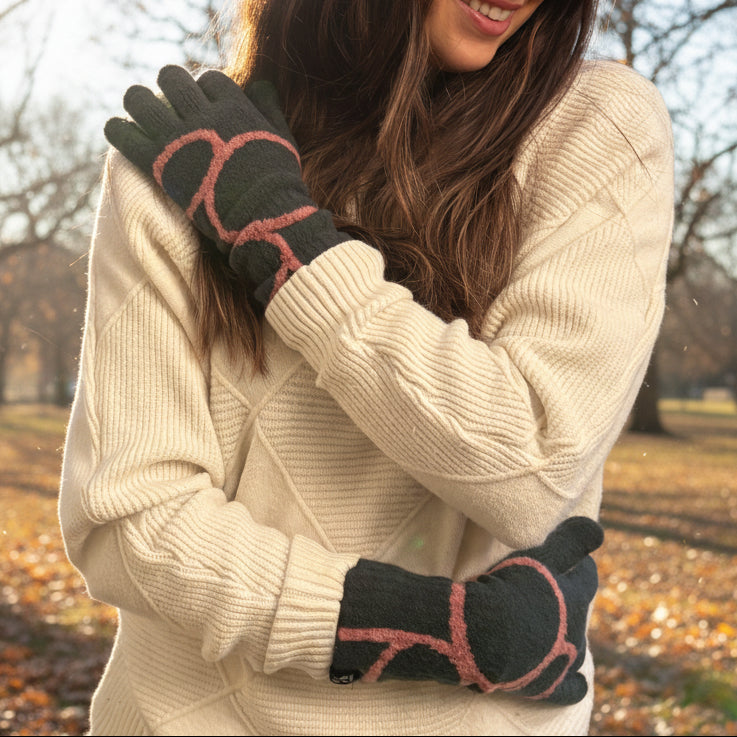 Person wearing a cream sweater and black gloves with red patterns, standing indoors.