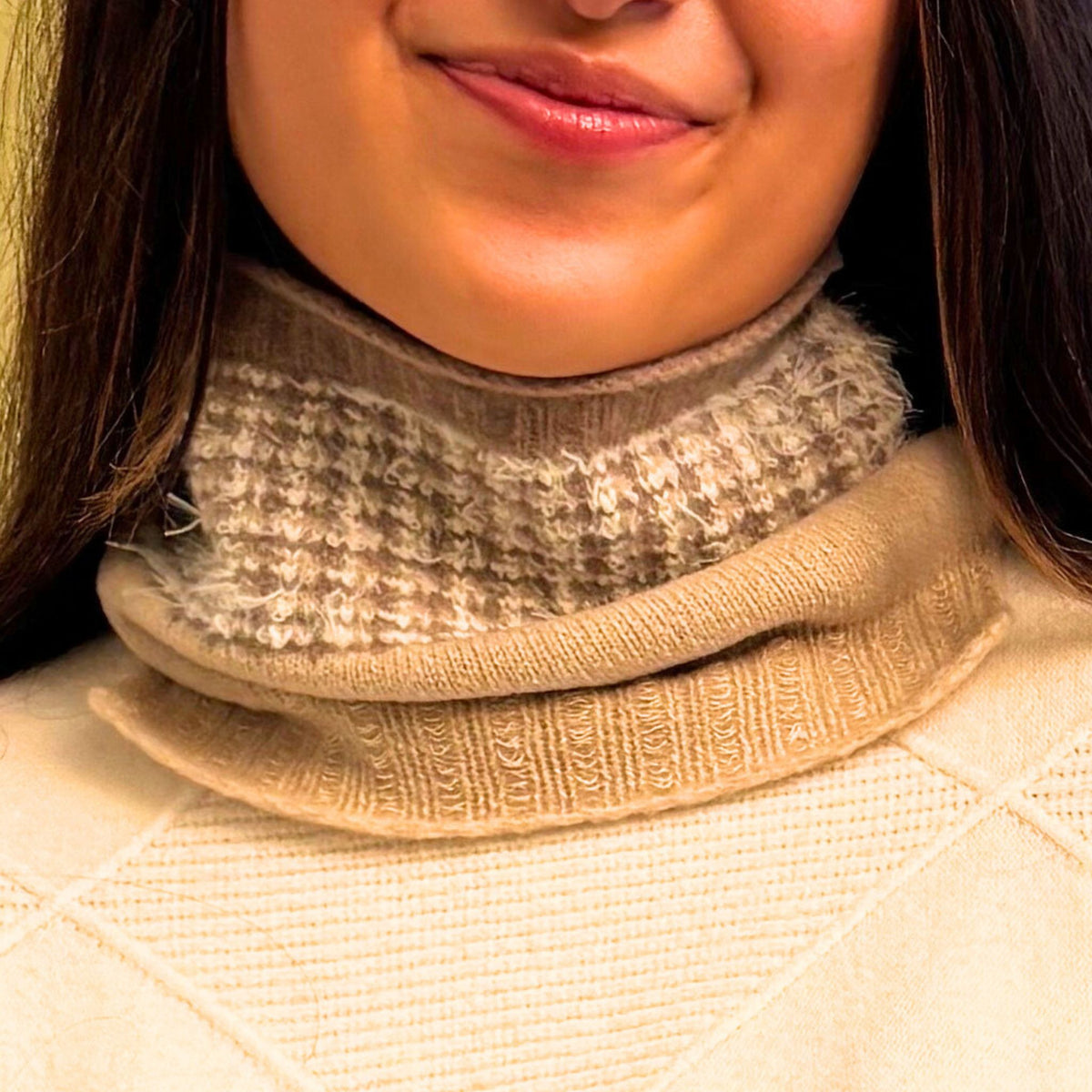Close-up of a person wearing a beige mini neck warmer scarf with a textured pattern.