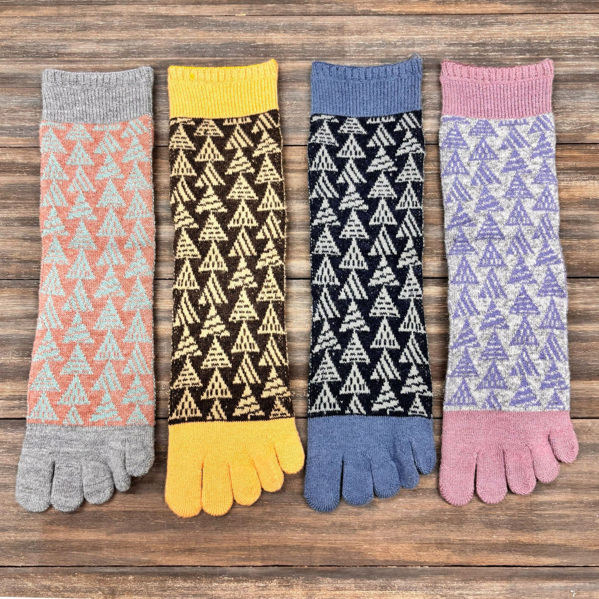 Four pairs of patterned toe socks on a wooden surface